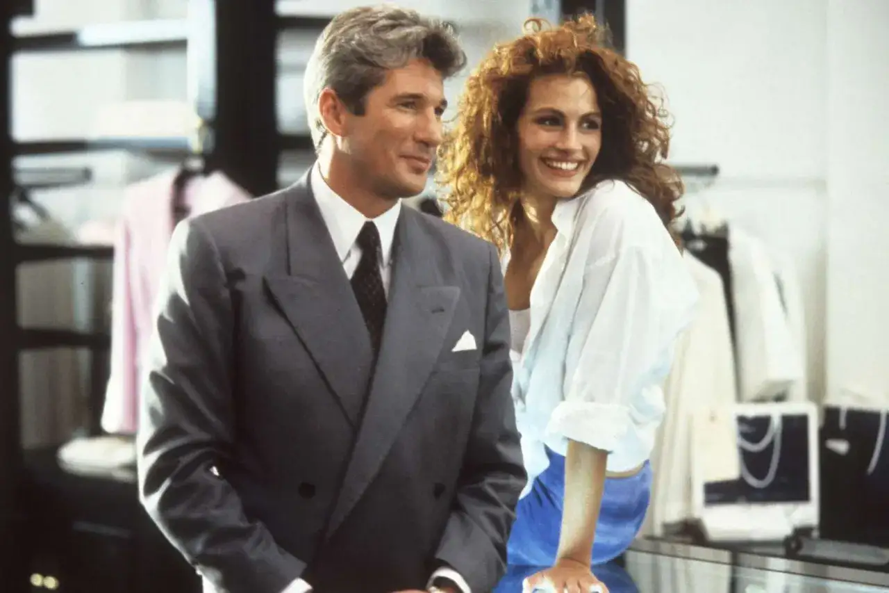 Elegancki mężczyzna w garniturze i uśmiechnięta, **pretty woman** z burzą rudych włosów stoją obok siebie w sklepie.