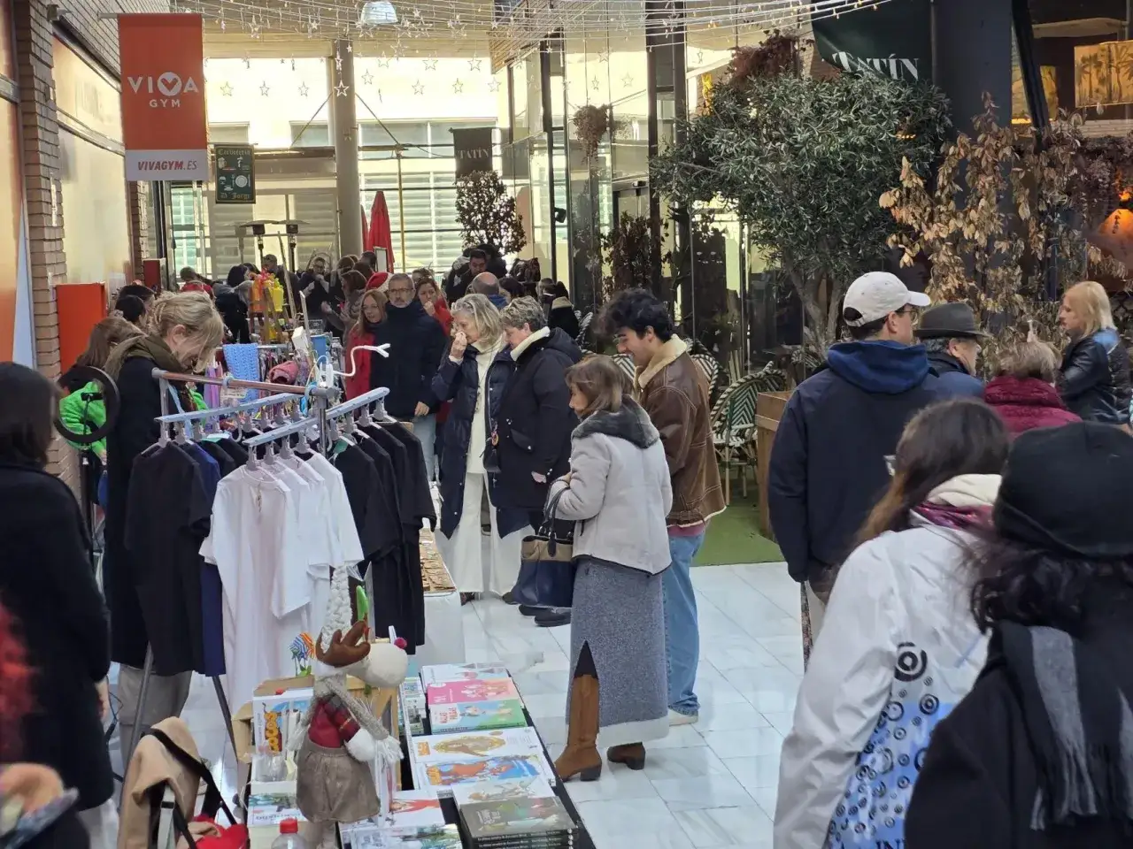 Gente comprando en un mercadillo frente al Auditorio de Zaragoza. Hay puestos de ropa y libros.