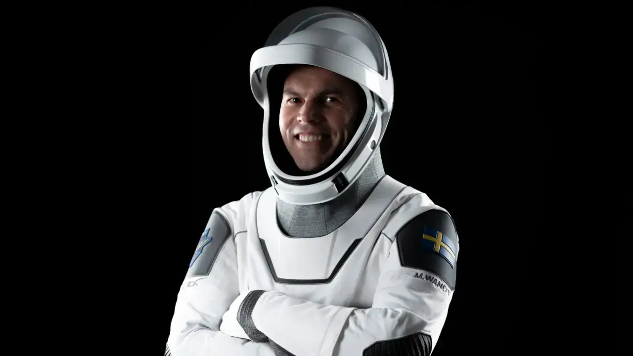 Marcus Wandt, en svensk astronaut, ler i sin rymddr&auml;kt med Sveriges flagga p&aring; axeln.