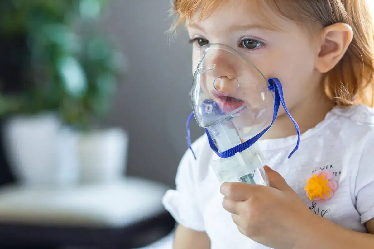 Małe dziecko z maską inhalatora, być może z powodu wirusa RSV.