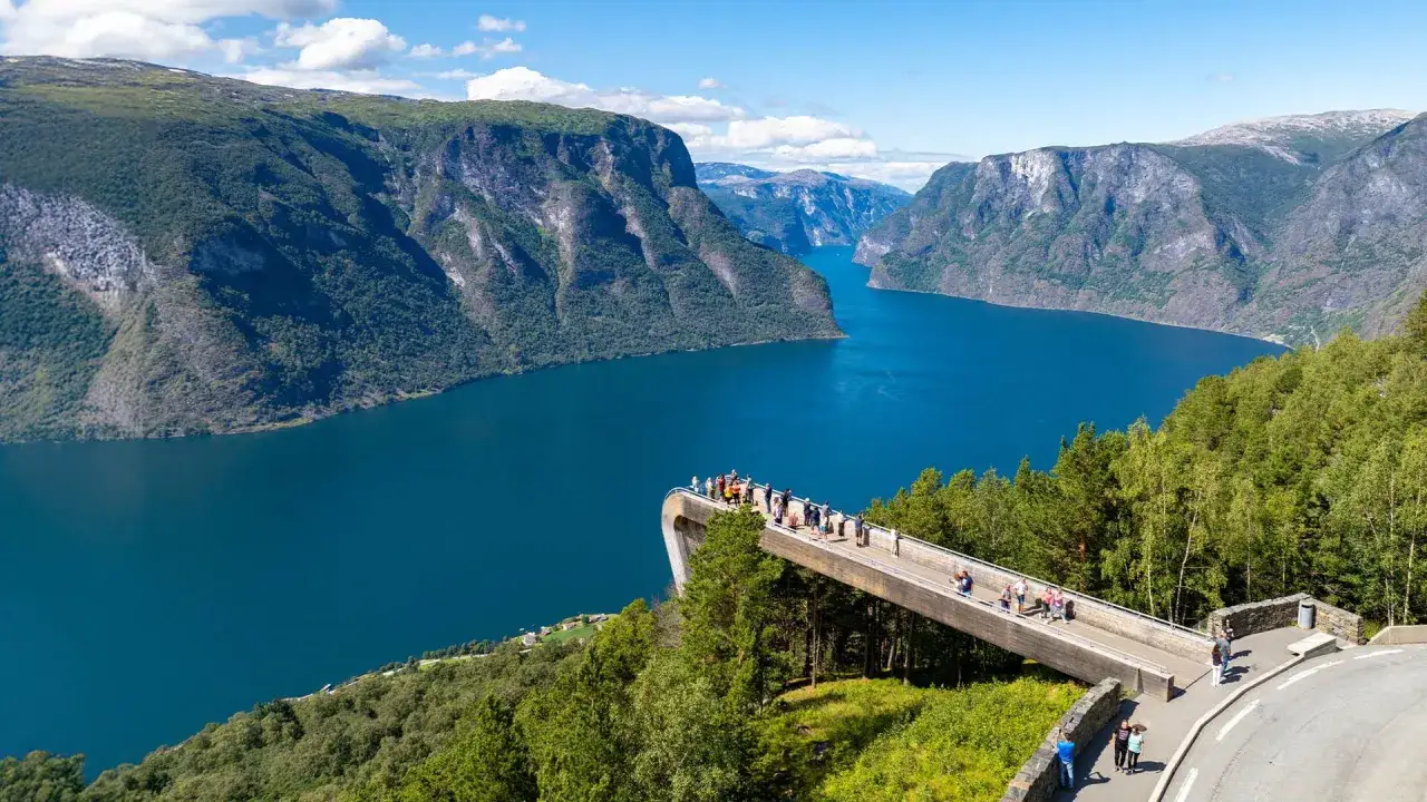 Widok na fiordy norweskie z platformy widokowej. Turkusowa woda otoczona stromymi, zielonymi górami.