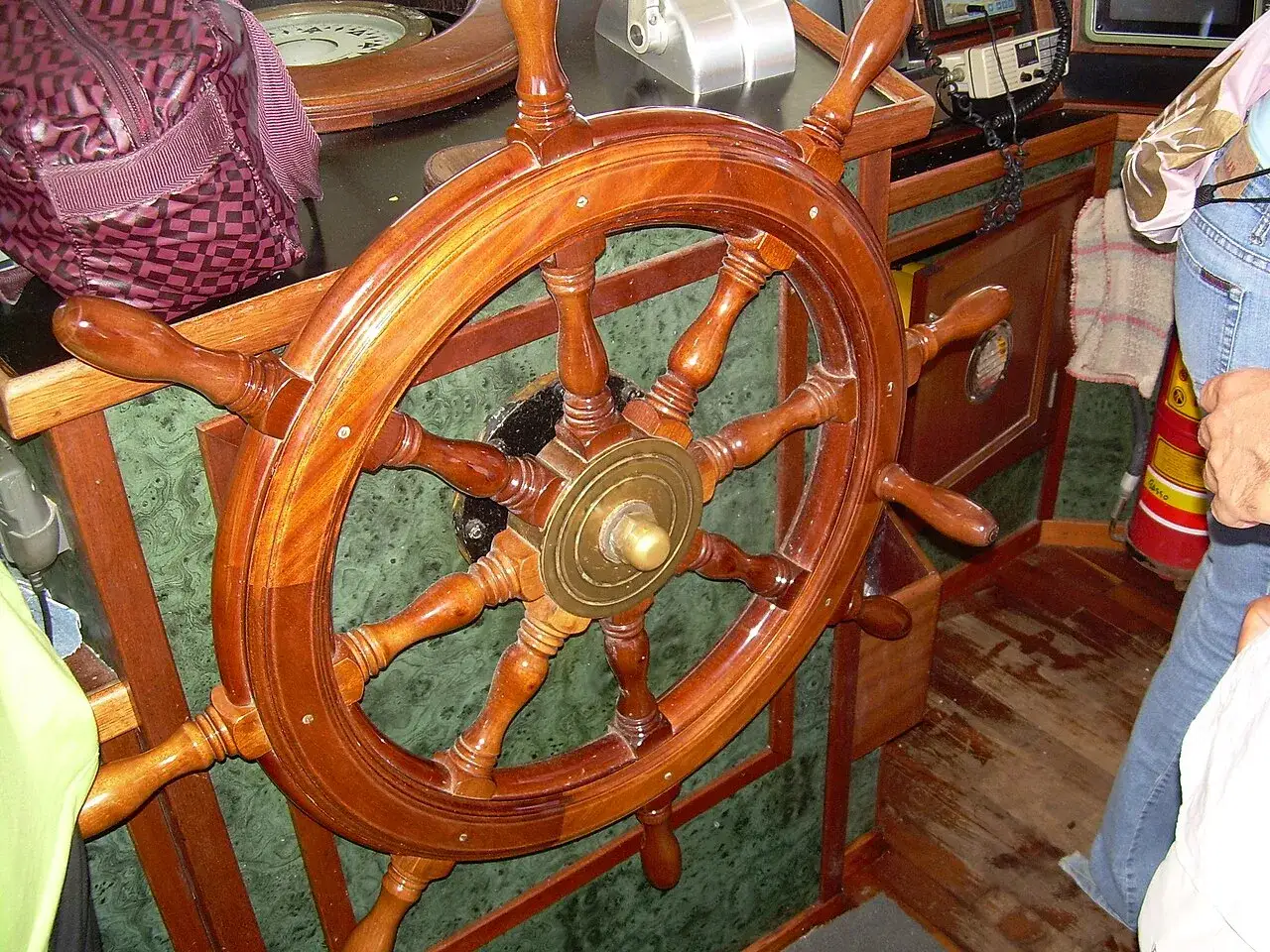 Il timone della nave, un grande volante in legno lucido, è pronto per guidare la rotta.