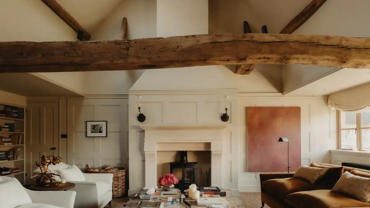 A living room with a stone fireplace, wood beams, and a warm color palette. The simplicity interior design creates a cozy and inviting atmosphere.