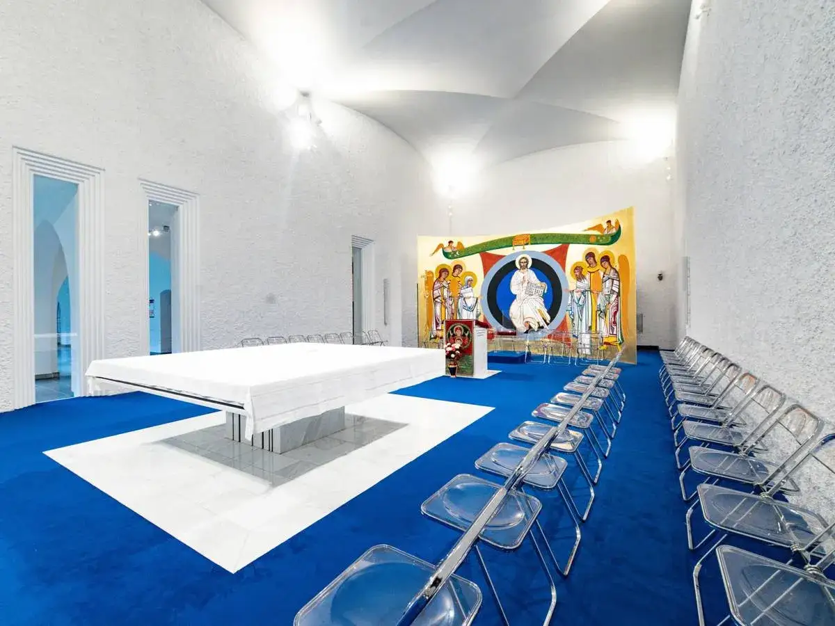 Moderner Raum im katholischen Priesterseminar mit Altar, bunten Wandgem&auml;lden und transparenten St&uuml;hlen.