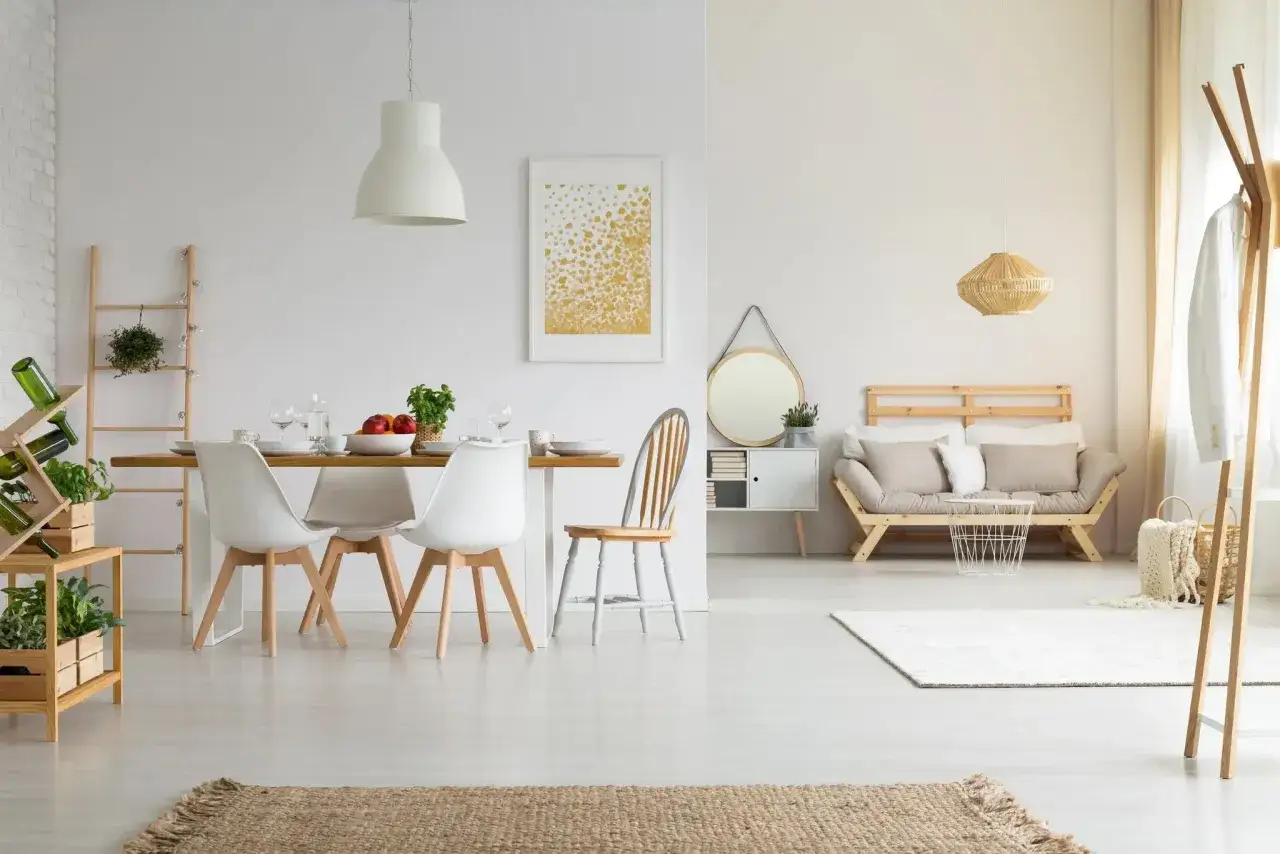 Comedor y sala con decoración estilo nórdico, muebles de madera clara, sillas blancas y un sofá cama de diseño minimalista.