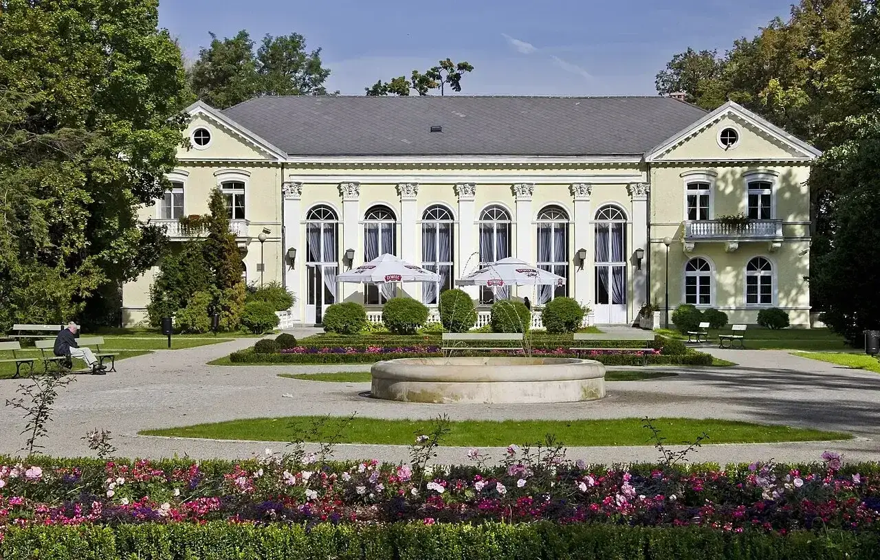 Elegancki pałac otoczony parkiem z fontanną i kwitnącymi rabatami. Idealne miejsce na relaks i odkrywanie **Cieplice atrakcje**.