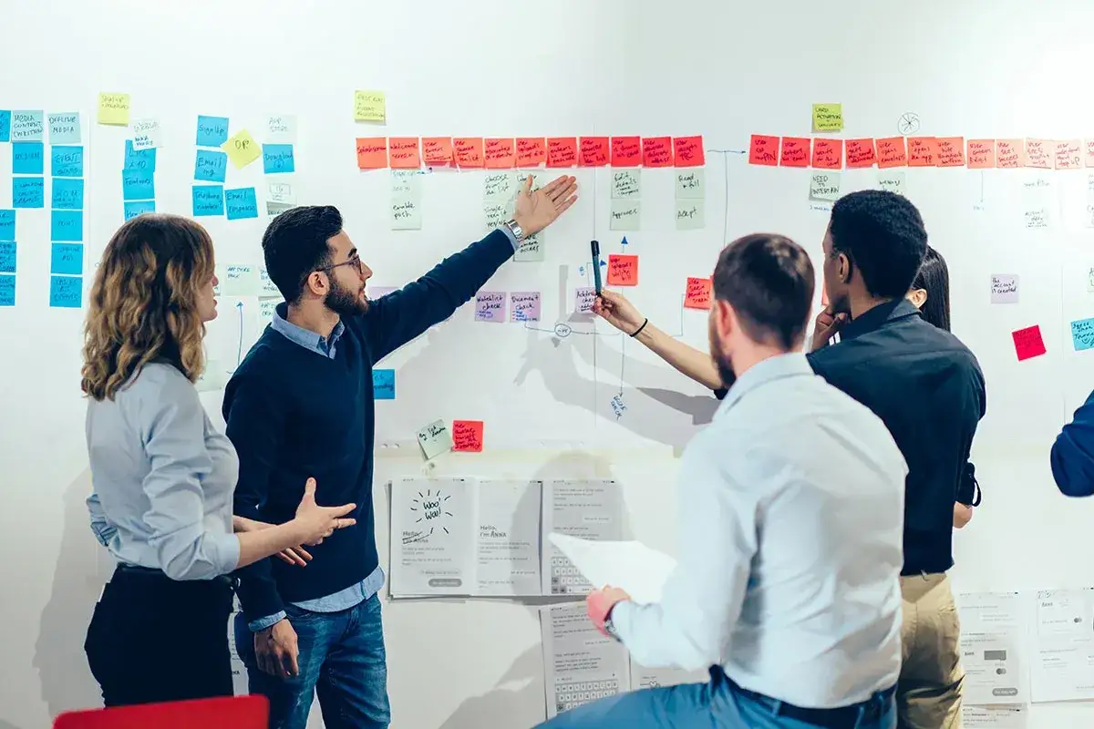 Team brainstorms on a whiteboard, mapping out steps to make change happen. Sticky notes and flowcharts illustrate their strategy.