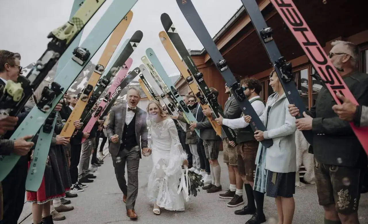Brautpaar läuft durch ein Spalier aus Skiern. Tolle Spalier Hochzeit Ideen für Wintersportfans!