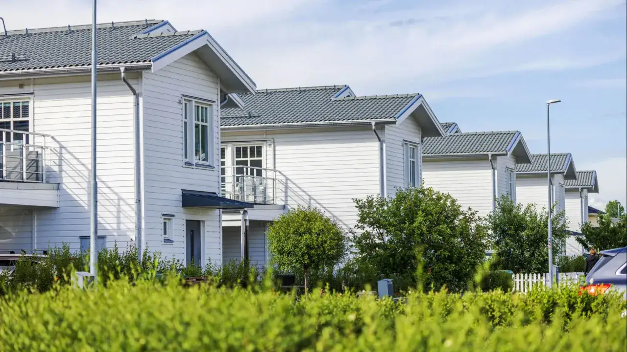 Rad av vita trähus med grå tak, en del av en nybyggd villaidyll där man kan behöva taxera om fastighet.