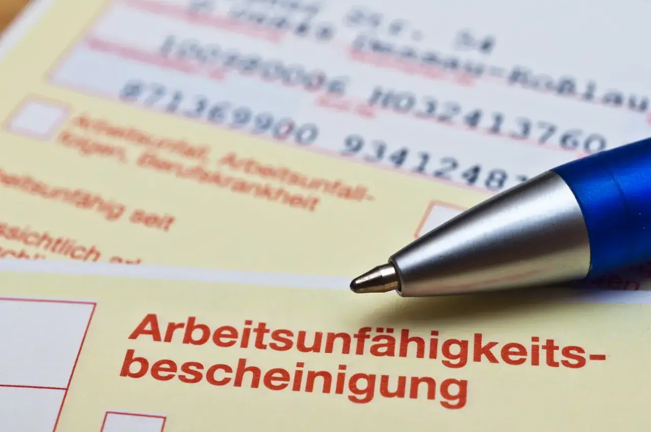 Arbeitsunfähigkeitsbescheinigung mit Stift. Ein Dokument, das bei einer Abmahnung wegen Krankheit relevant sein könnte.