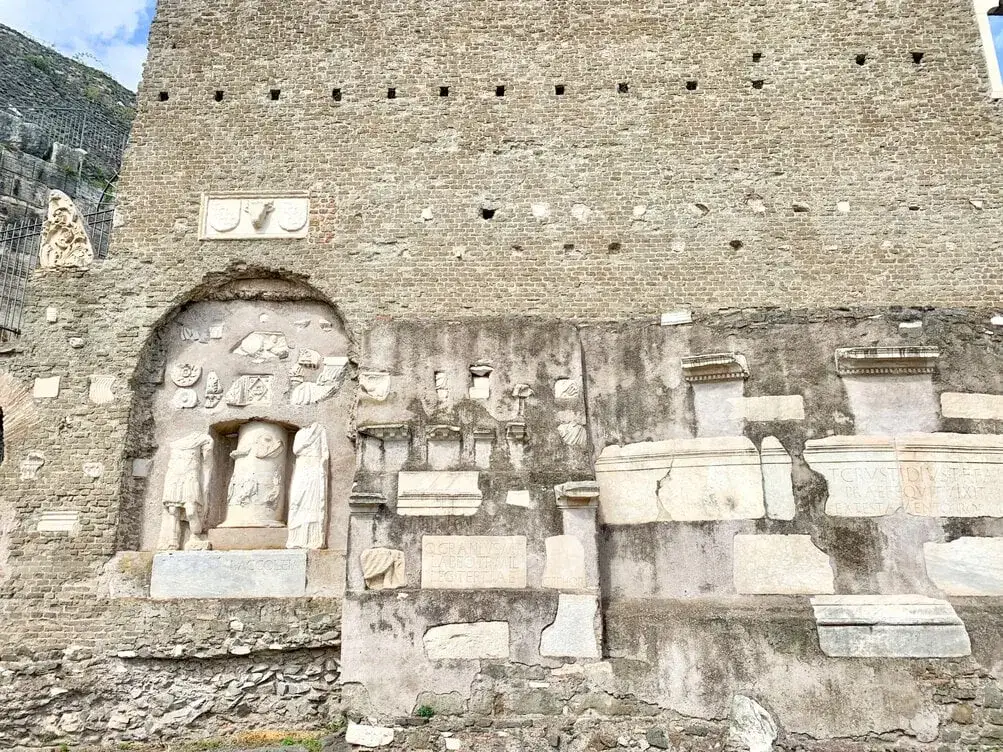 Antika ruiner längs Via Appia visar fragment av statyer och inskriptioner, en påminnelse om Roms historia.