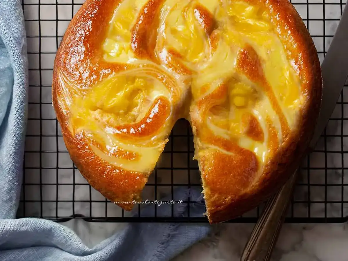 Torta nua con crema pasticcera, dorata e invitante, con un vortice di dolcezza che promette un morso delizioso.