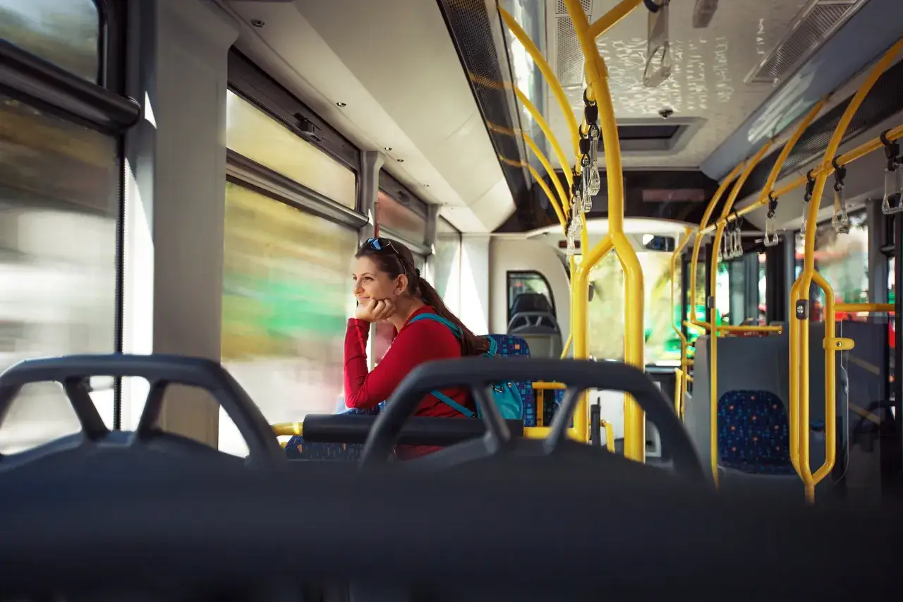 Kobieta w czerwonej bluzce podróżuje autobusem, zastanawiając się, czy w Bułgarii jest bezpiecznie.