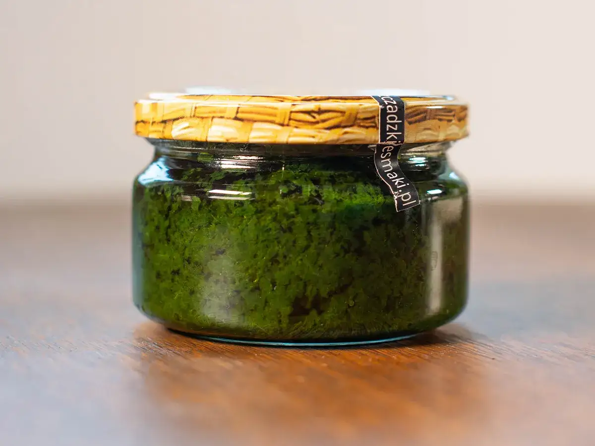 Słoiczek z intensywnie zielonym pesto z czosnku niedźwiedziego, gotowy do wzbogacenia smaku Twoich potraw.