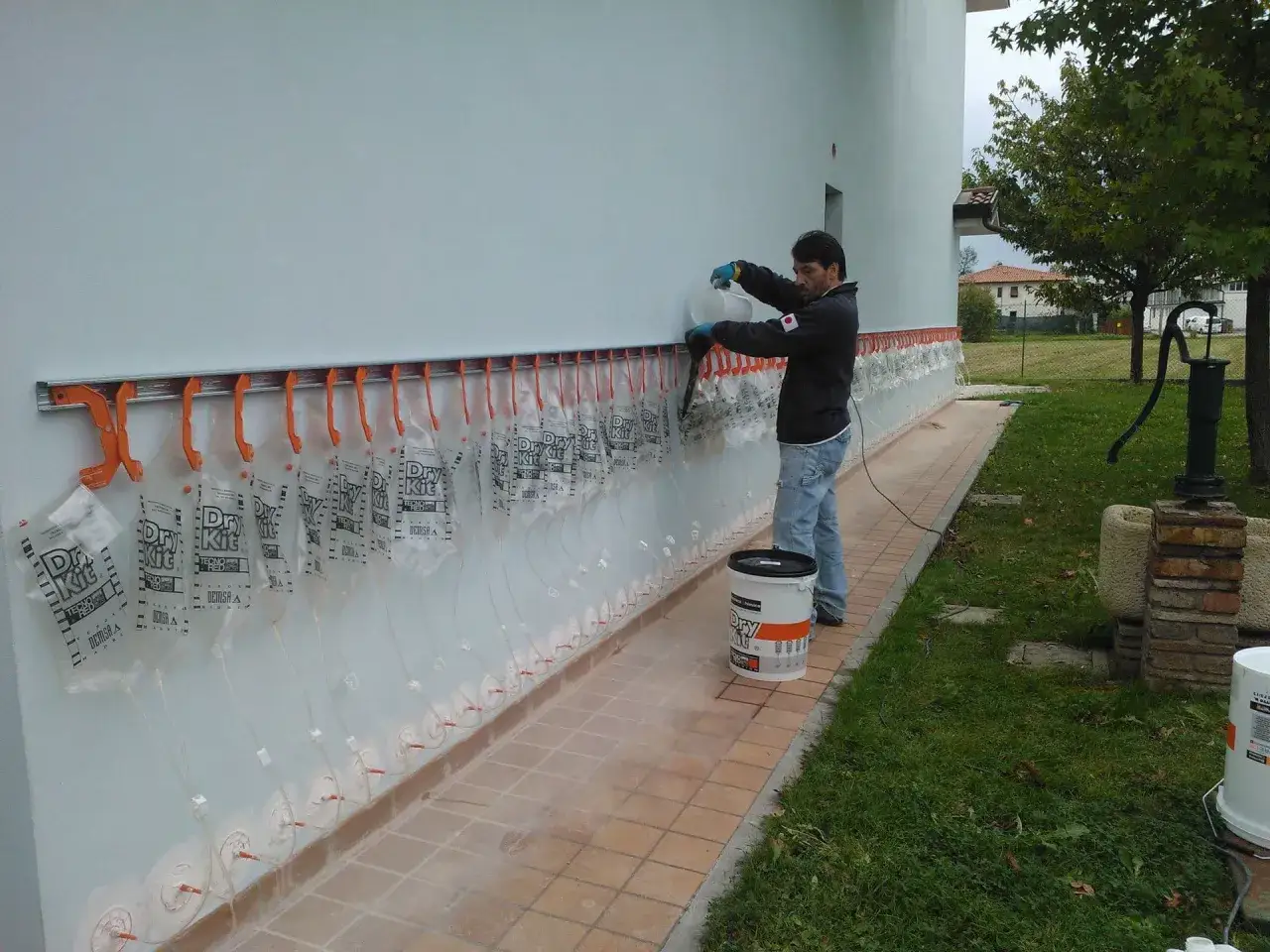 Installazione di sistemi anti umidità di risalita: un operaio riempie le sacche per un trattamento efficace.