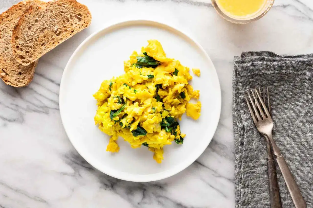 Uova strapazzate con spinaci, perfette per una dieta leggera. Accompagnate da pane tostato.