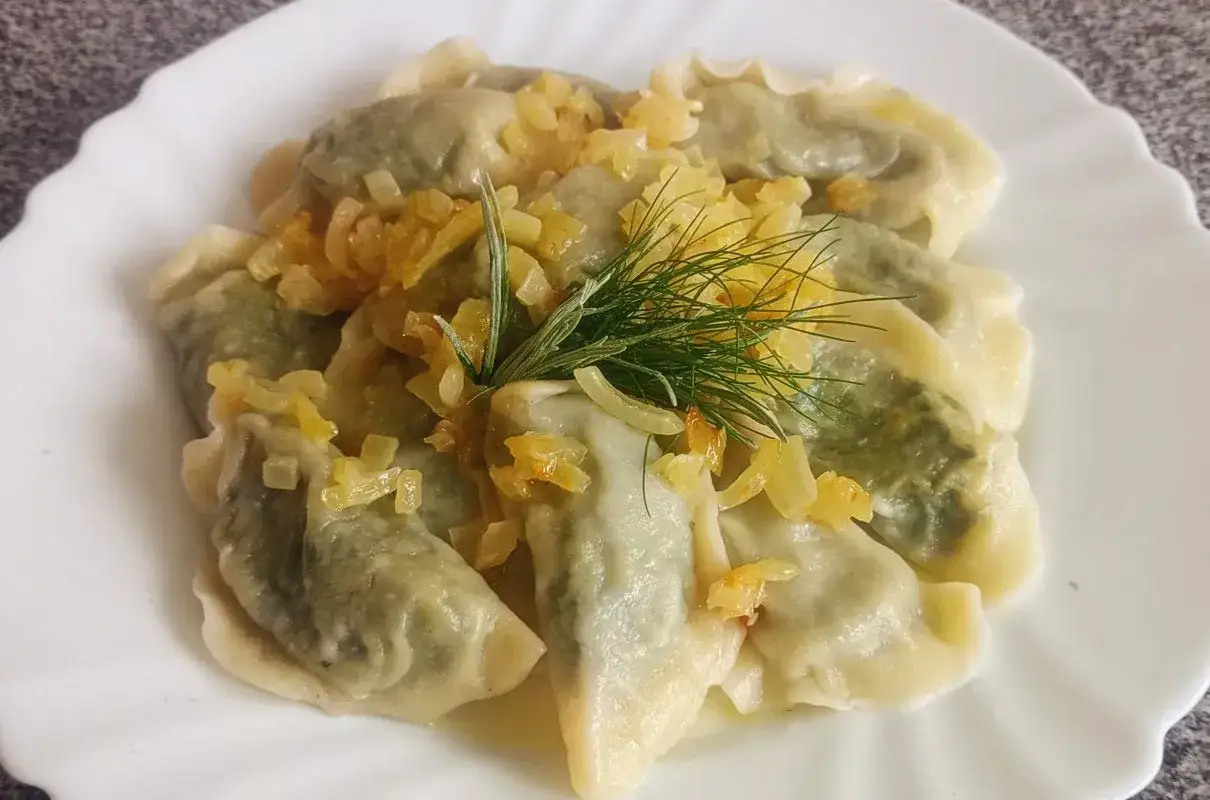 Pyszne pierogi ze szpinakiem, polane skwarkami i udekorowane koperkiem. Idealne na obiad!