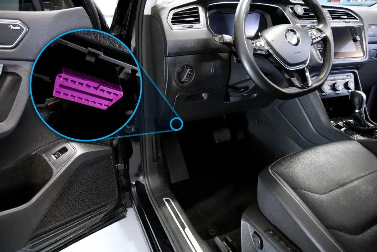 Conexi&oacute;n OBD p&uacute;rpura visible en el interior de un coche, lista para diagn&oacute;stico.