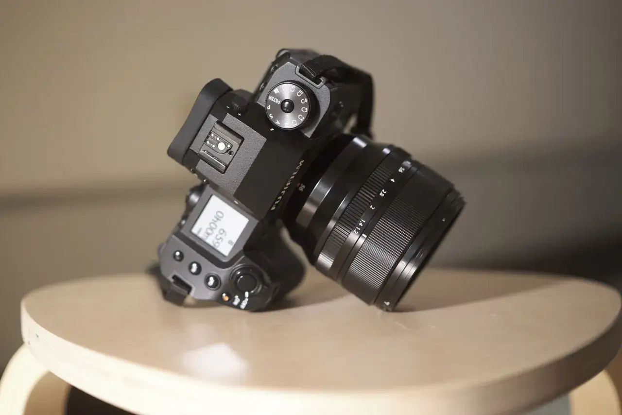 Un appareil photo Fujifilm XH2, prêt pour l'aventure photographique, repose sur un tabouret en bois.