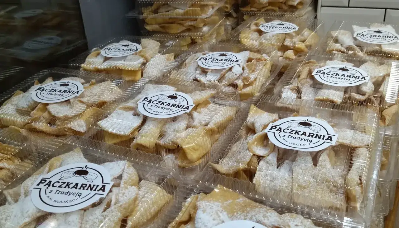 Pączki i faworki w paczkarni, gotowe na tłusty czwartek. Słodkości posypane cukrem pudrem kuszą swoim wyglądem.