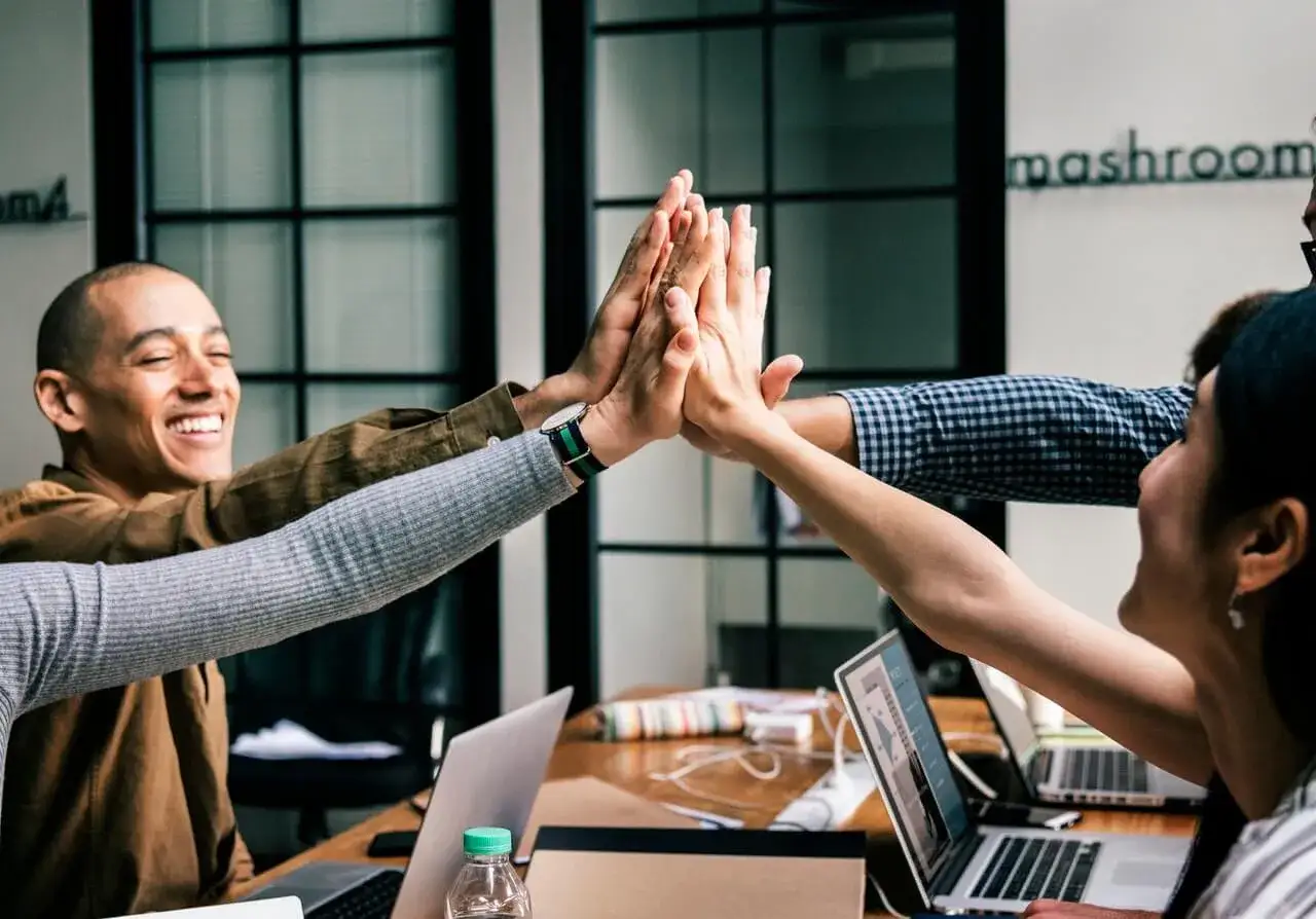 Team celebrates a successful outcome after a collaborative process. Their high-five signifies the purpose of their work achieved.
