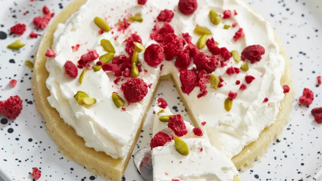 En saftig citron kladdkaka med fluffig grädde, toppad med hallon och pistagenötter. En perfekt dessert för alla tillfällen.