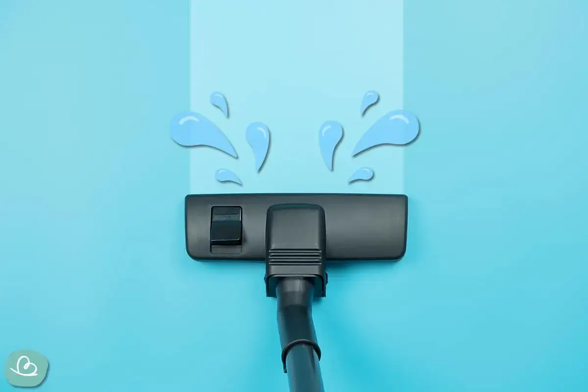Staubsauger saugt Wasser auf. Blaue Wassertropfen spritzen nach oben, während der schwarze Saugfuß über den hellblauen Hintergrund fährt.