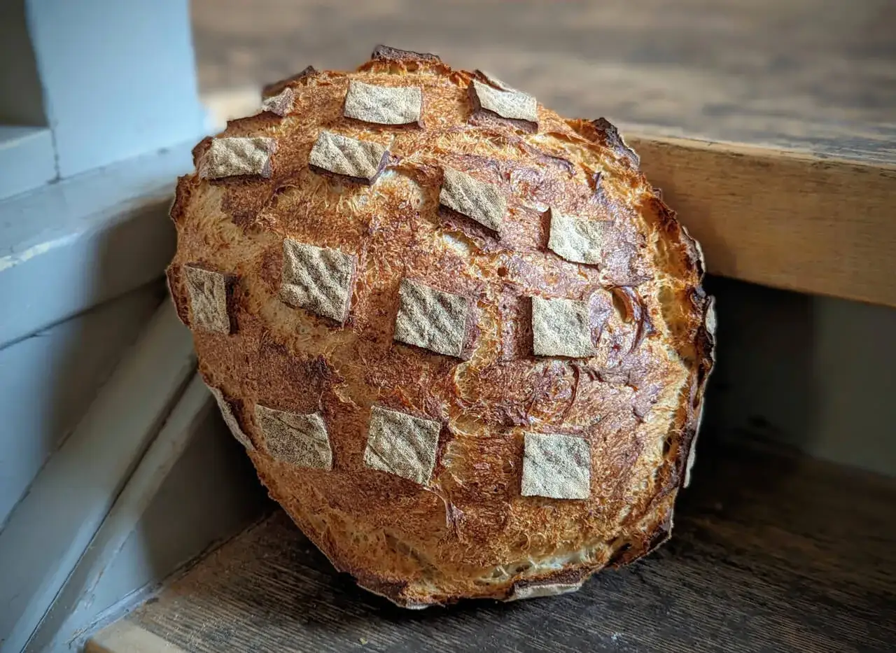 Ein rustikales Porridge Brot mit knuspriger Kruste und quadratischen Teigst&uuml;cken, die wie ein Schachbrettmuster angeordnet sind.