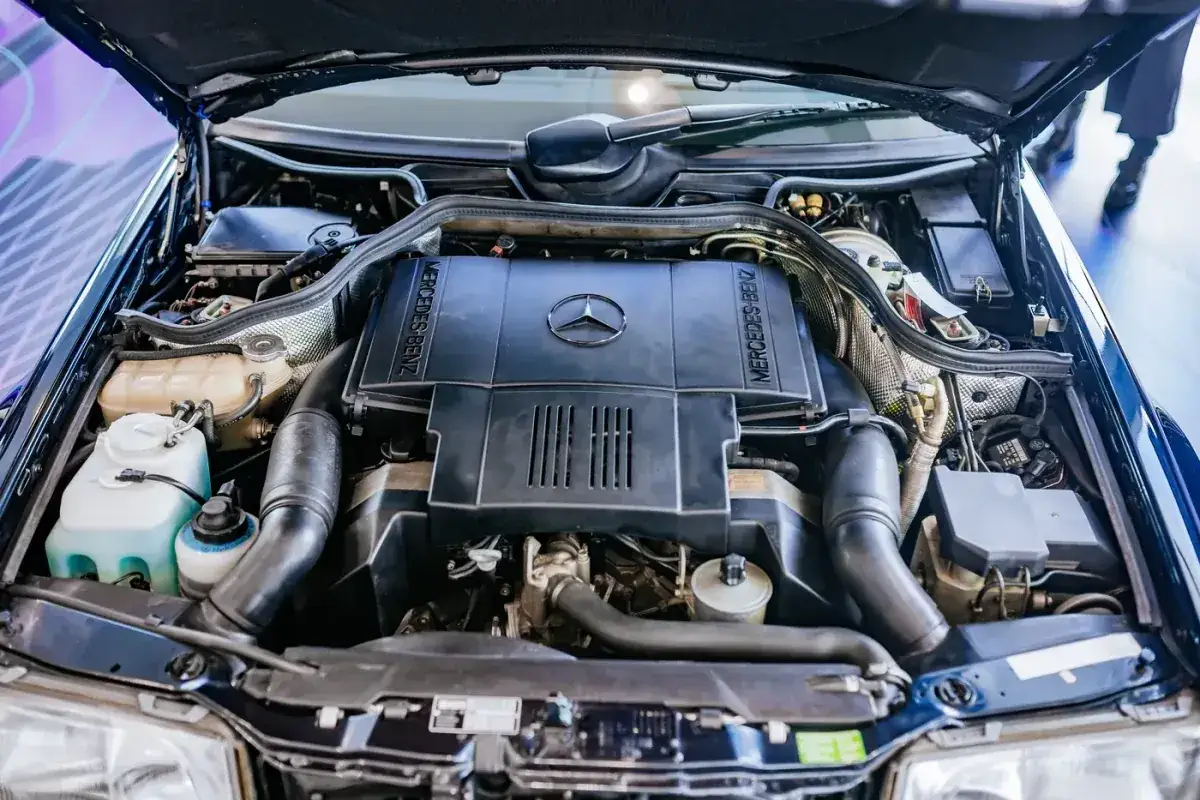 Silniki Mercedes W124, czarny, schludny, z logo gwiazdy na pokrywie.