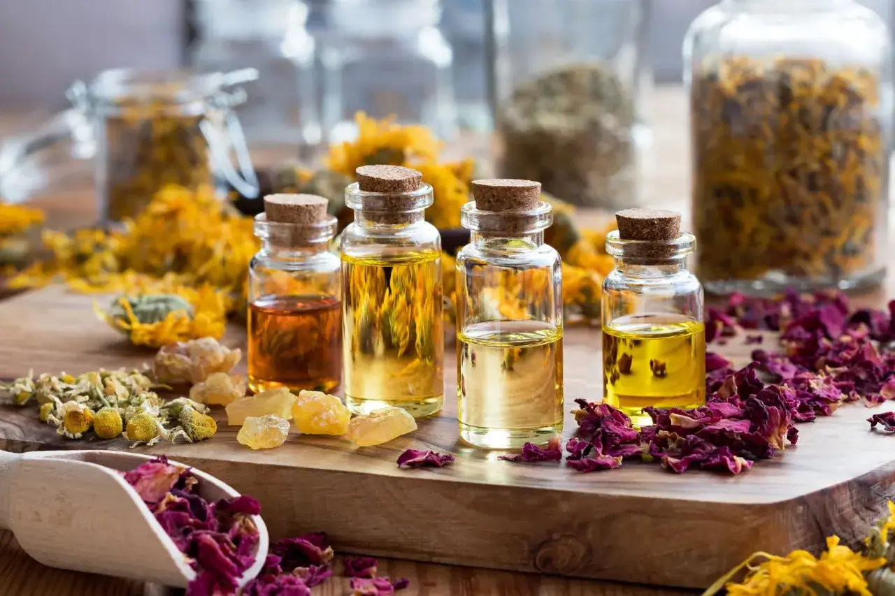 Botellas con l&iacute;quidos dorados y &aacute;mbar, rodeadas de p&eacute;talos de rosa secos, flores de manzanilla y cal&eacute;ndula. &iquest;Cu&aacute;les son los aceites esenciales?