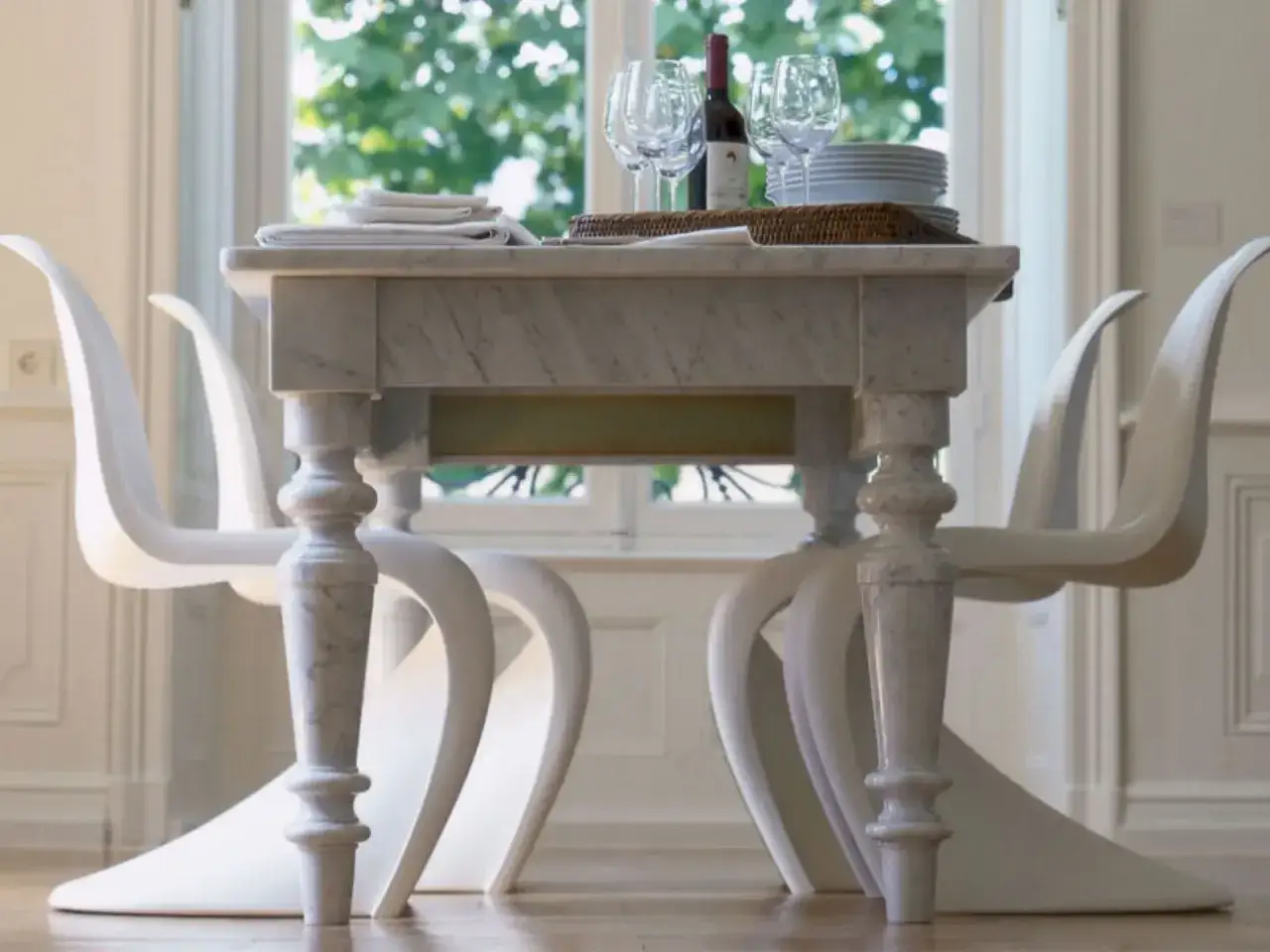 Un tavolo in marmo con sedie bianche dalle forme sinuose. Un esempio di come abbinare le sedie al tavolo per un look moderno ed elegante.
