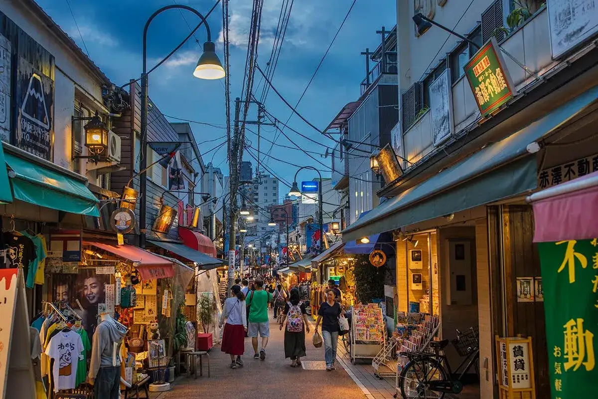 En livlig gata i gamla Tokyo med butiker, skyltar och folk som promenerar.