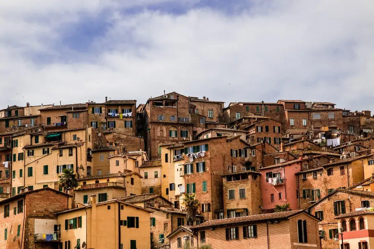 Un panorama di tetti e case in mattoni a Siena, con panni stesi al sole. Un assaggio di cosa vedere a Siena, tra vicoli e storia.