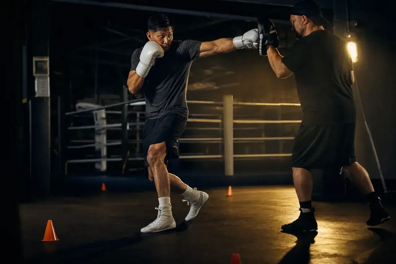 Boxer trains with coach, practicing punches. This intense workout hones skills, a tradition dating back to where did shadow boxing come from.