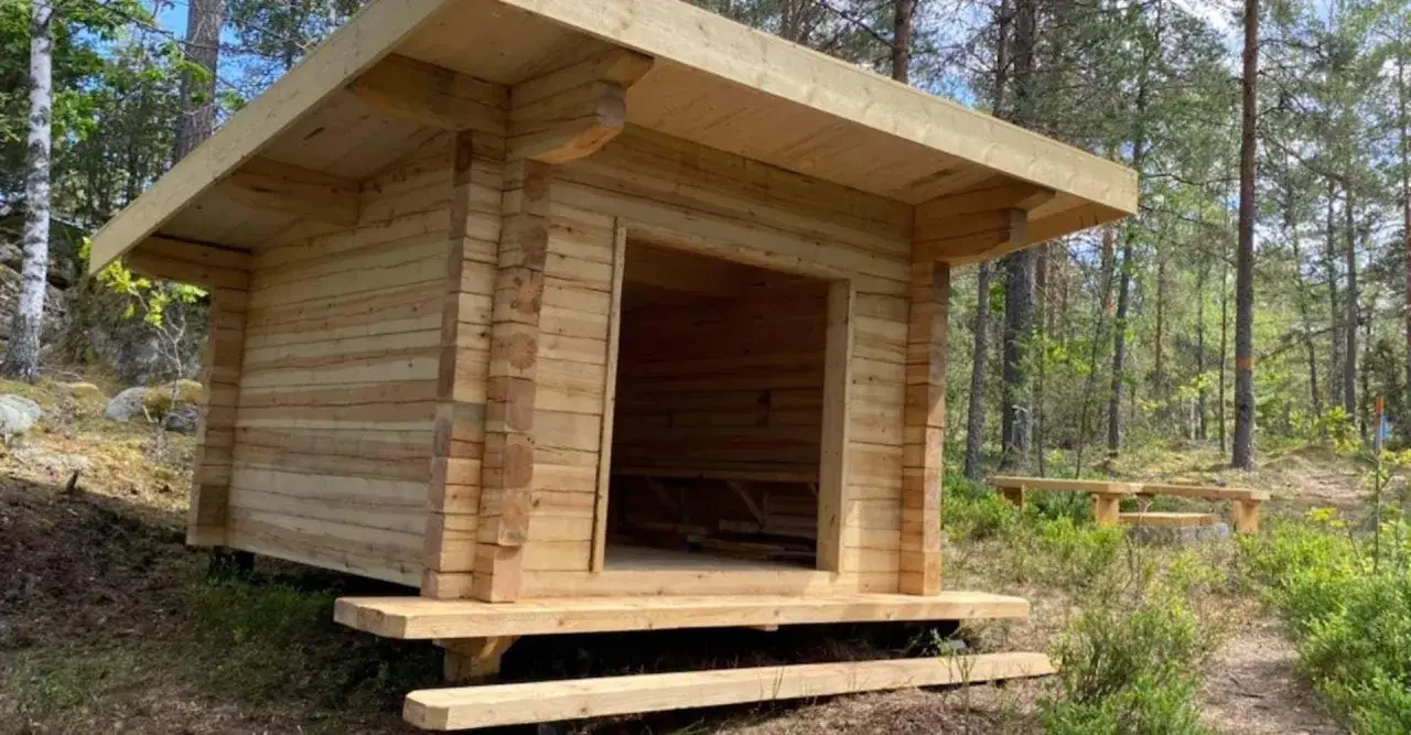 Nybyggt vindskydd i skogen, redo f&ouml;r &auml;ventyr. Enkel tr&auml;konstruktion med b&auml;nkar utanf&ouml;r.