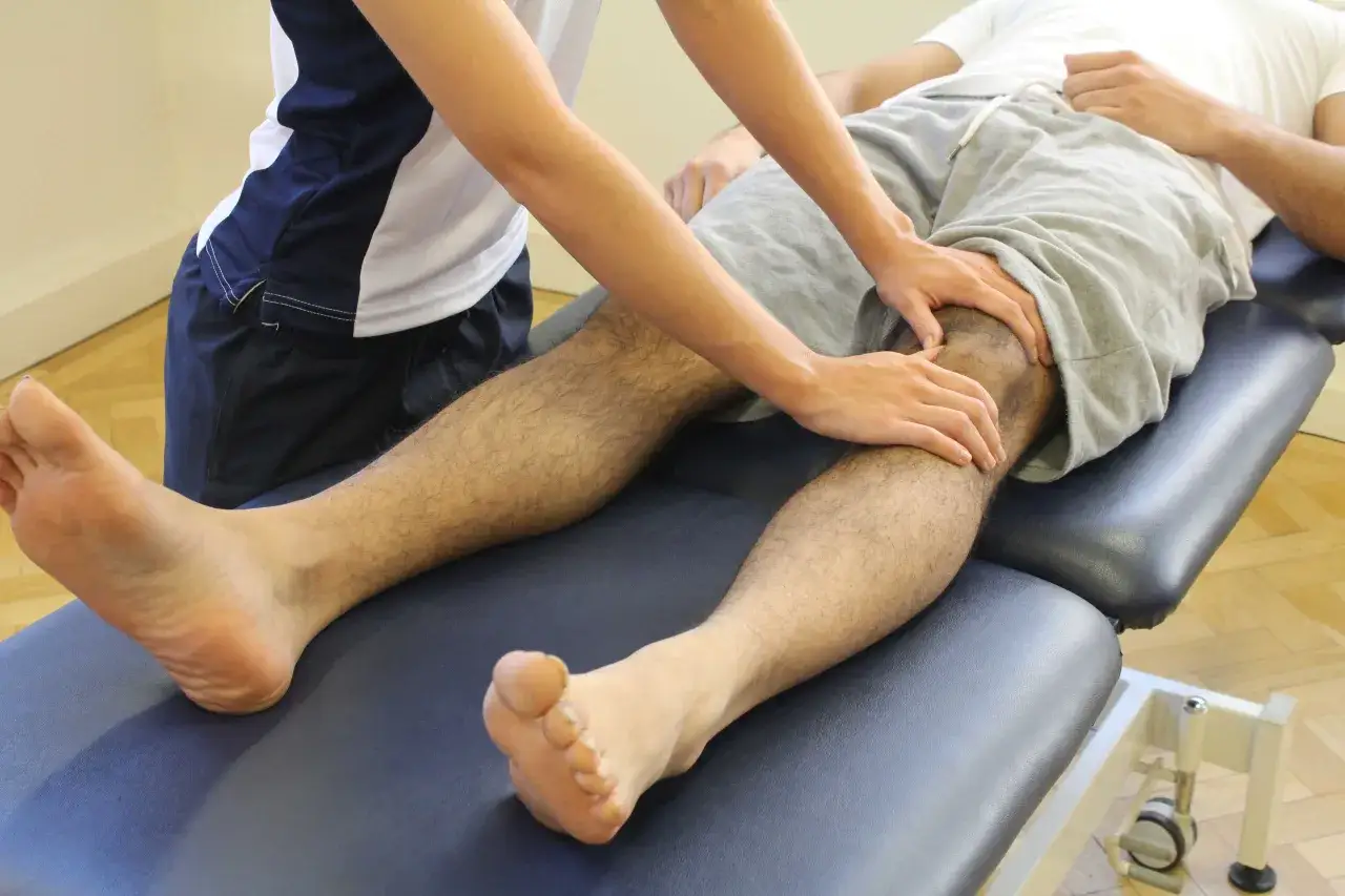 Fizjoterapeuta bada kolano pacjenta. Unikaj ruchów, które nasilają ból przy chondromalacji rzepki.
