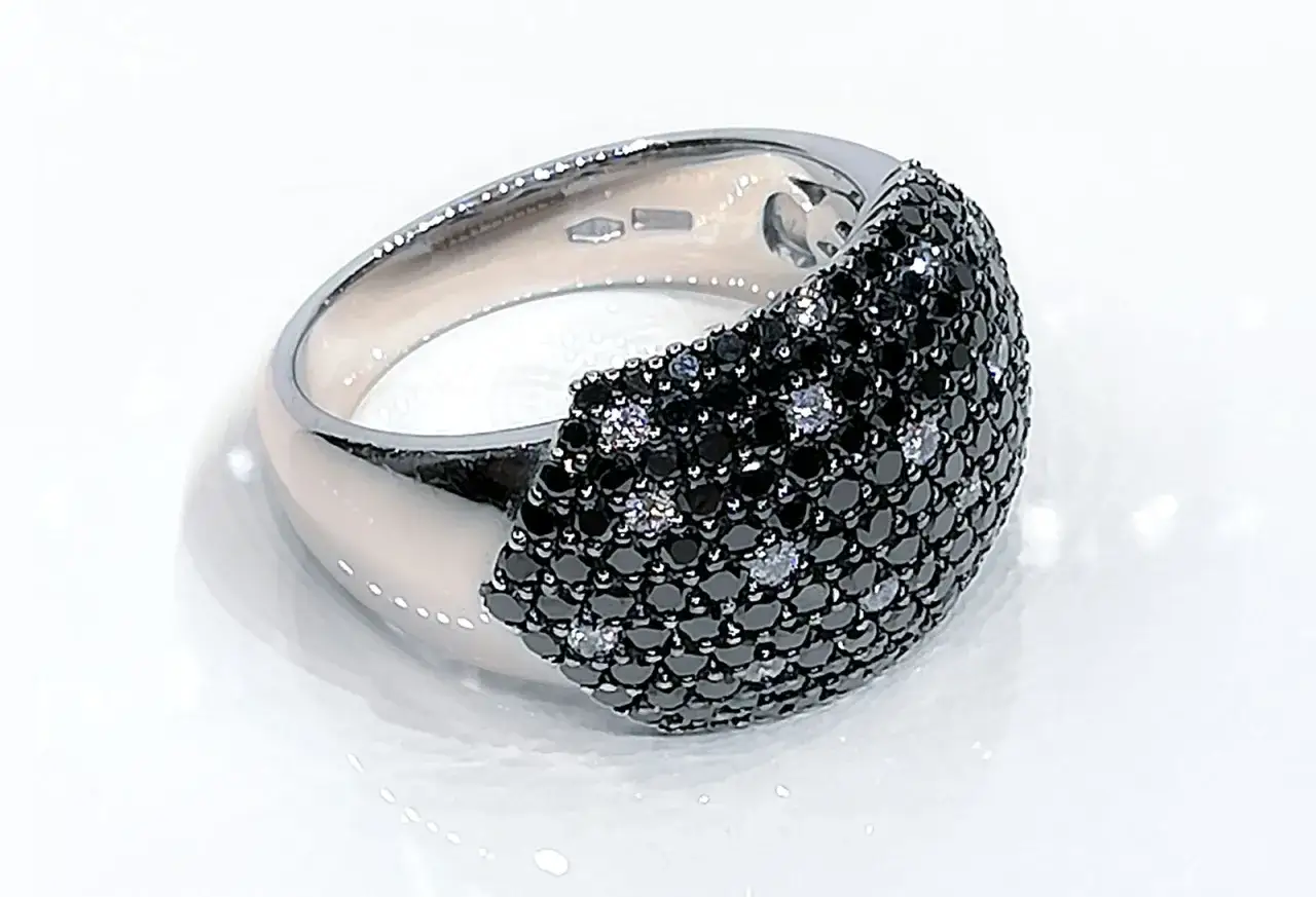 Anello in oro bianco con pav&eacute; di diamanti neri e bianchi, un vero diamante nero che cattura lo sguardo.