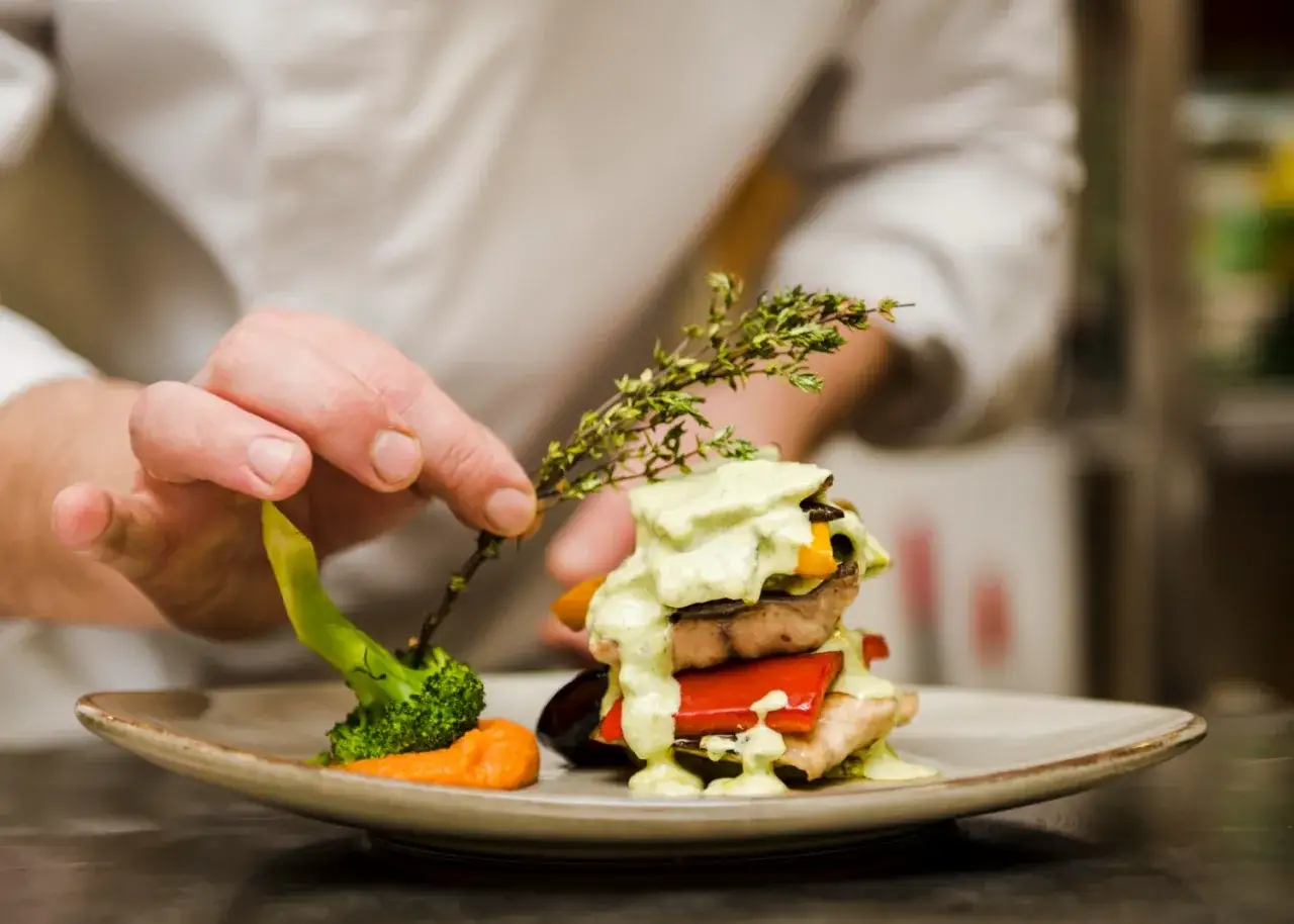 Chef decora un plato con brócoli y hierbas. Un paso más para aprender a cocinar.