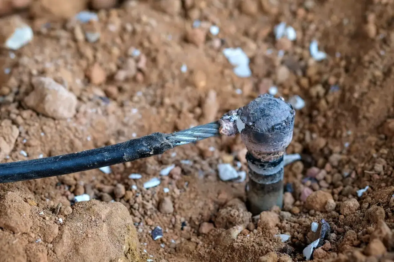 Uziemienie instalacji elektrycznej: metalowa bednarka połączona z kablem, wbita w ziemię.