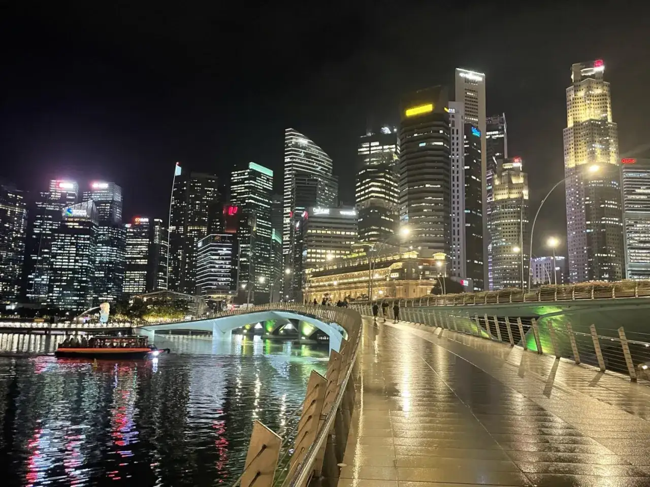 Wieczorny Singapur, lśniące drapacze chmur i rzeka. Spacerując po mokrym moście, czujesz się bezpiecznie.