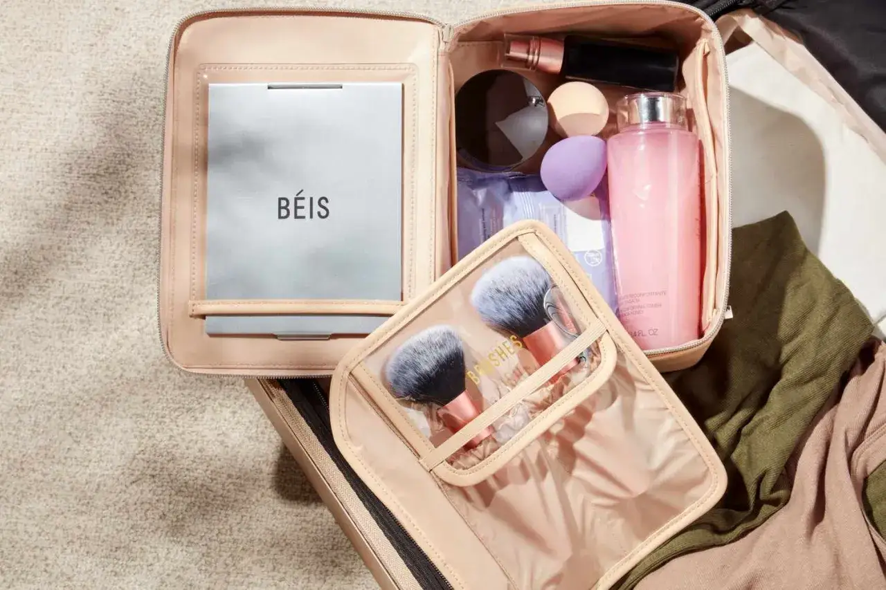 Smink i handbagage: en rosa necess&auml;r med spegel, sminkborstar, puder, foundation och toner. Perfekt f&ouml;r resan.