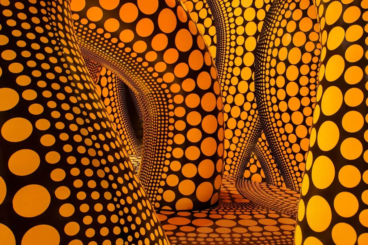 Wciągająca instalacja z kropkami Yayoi Kusama. Pomarańczowe kropki na czarnym tle tworzą iluzję nieskończoności.