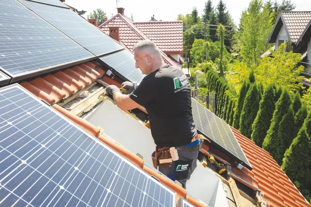 Monter montuje panele fotowoltaiczne na dachu, zwiększając efektywność energetyczną domu.