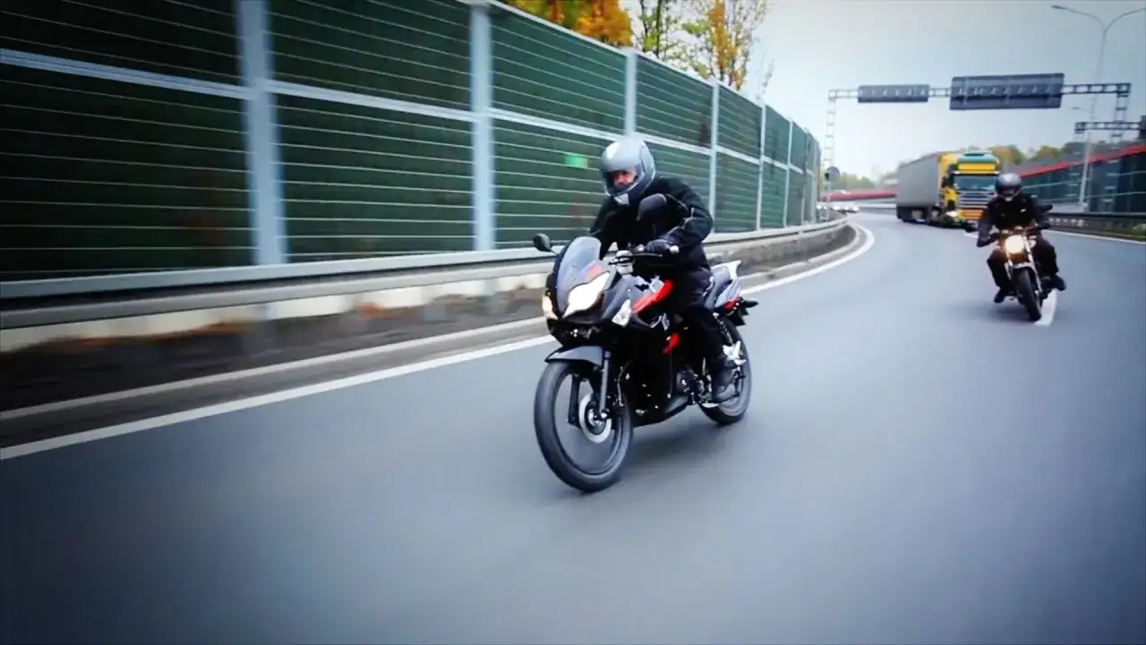 Motocyklista na czarnym motocyklu kat a1 jedzie autostradą obok ekranów akustycznych.