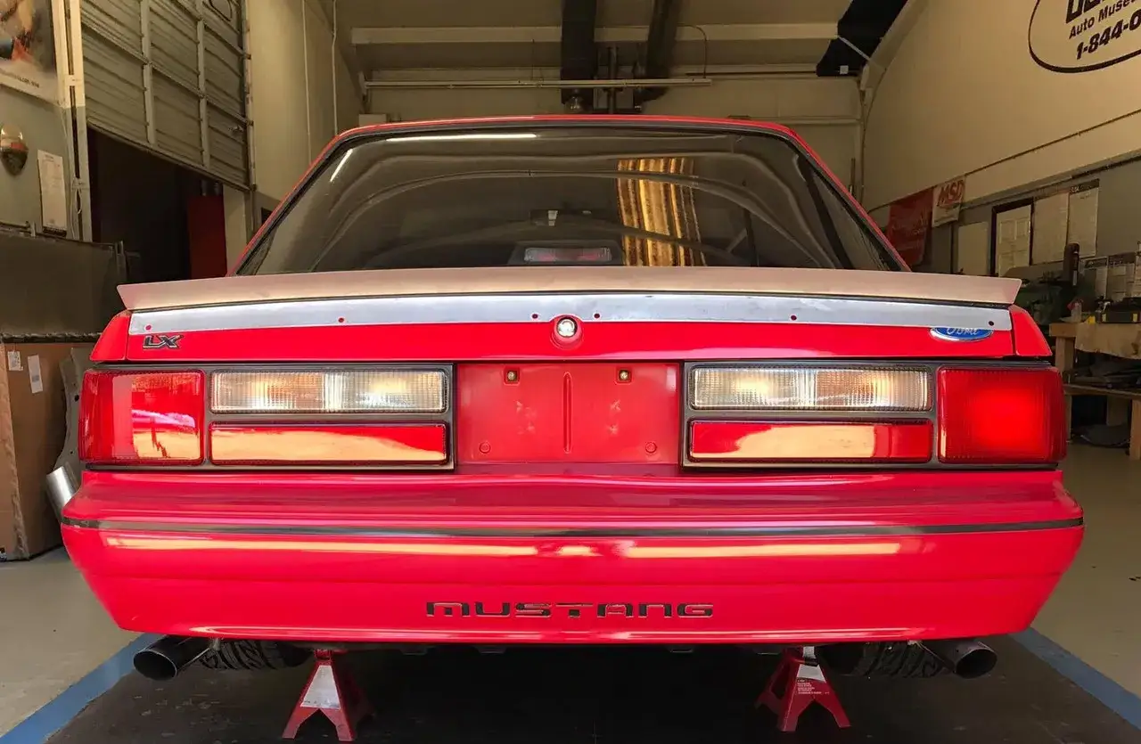 Czerwony Mustang LX z dyskretnym spojlerem na klapie bagażnika, gotowy do modyfikacji.