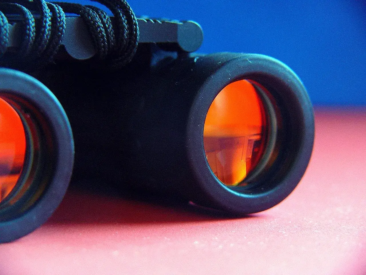Primo piano di un binocolo con lenti arancioni riflettenti, pronto per esplorare il mondo.