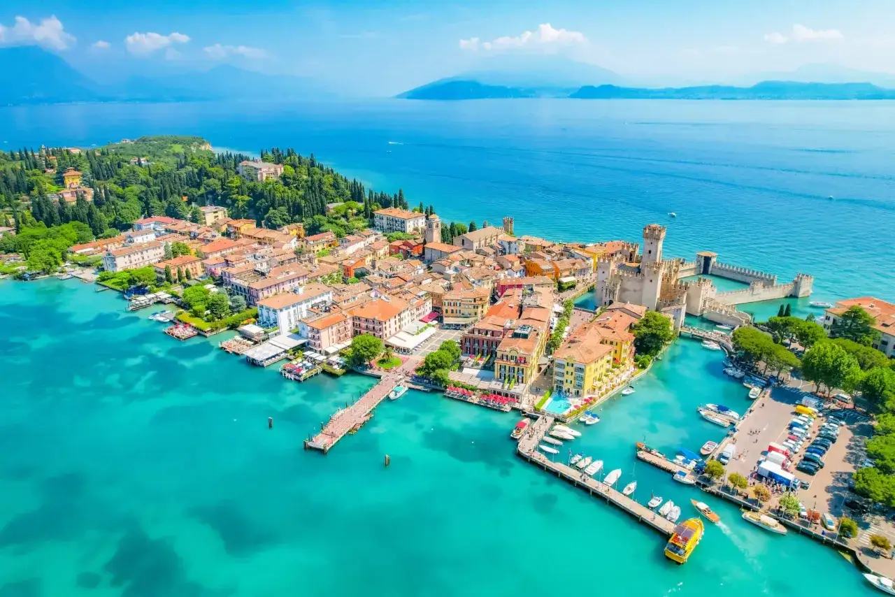 Malownicze jezioro Garda z urokliwymi plażami, zamkiem i kolorowymi budynkami.
