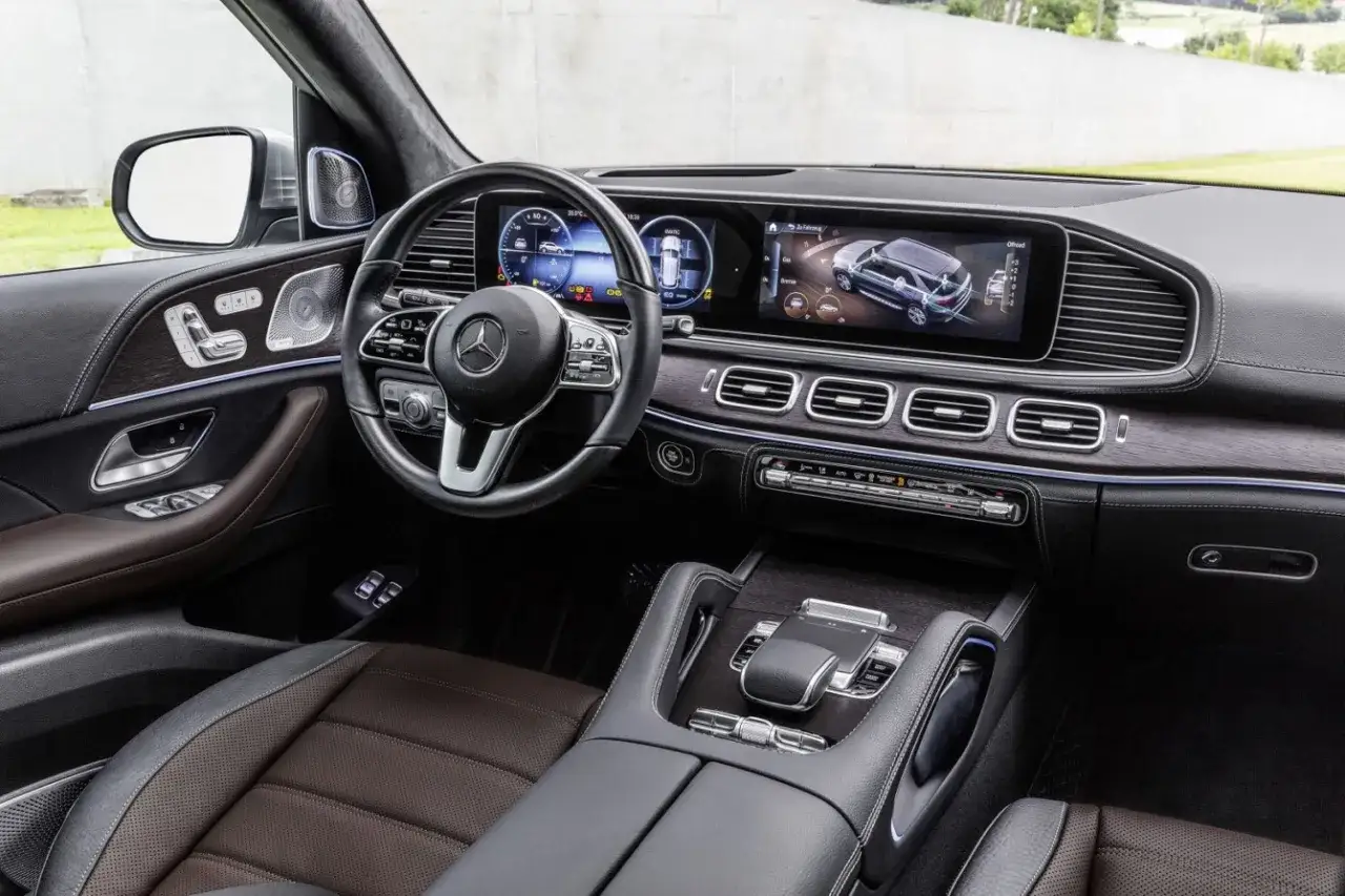 Wnętrze luksusowego Mercedesa GLE 400d z nowoczesnym panelem cyfrowym i komfortowymi, brązowymi fotelami.