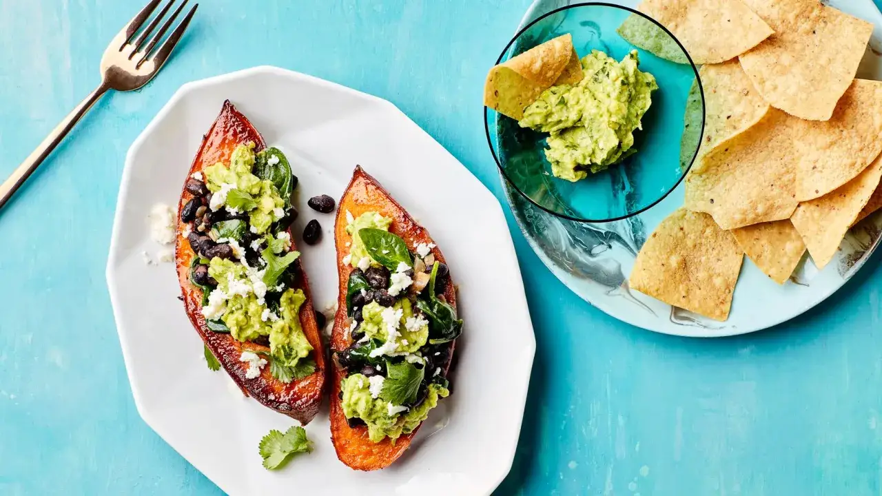 Dwa połówki pieczonych batatów z czarną fasolą, awokado i serem feta. Czy bataty są zdrowe? Tak, to świetny wybór!