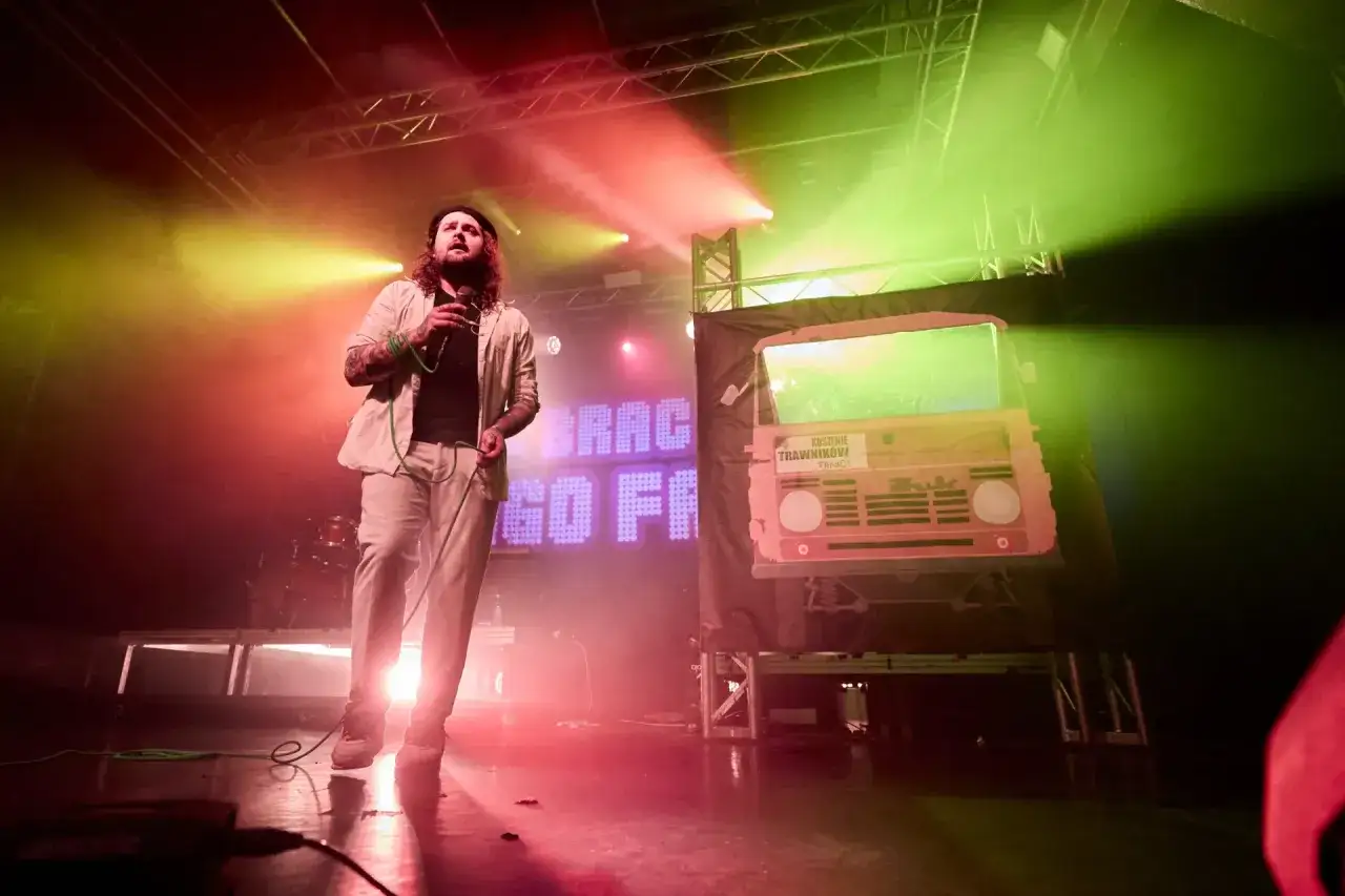 Wokalista na scenie, w tle neonowy napis i atrapa Żuka. Koncert pełen energii, jakby figo i samogony tańczyły w świetle reflektorów.